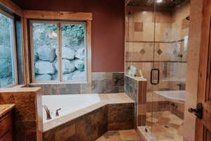 Bathroom featuring a garden tub, a stall shower, and vanity