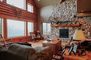 Living room featuring plenty of natural light, high vaulted ceiling, a fireplace, log walls, and hardwood / wood-style flooring