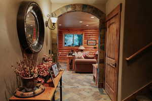 Corridor with light stone finish floors, recessed lighting, arched walkways, and rustic walls