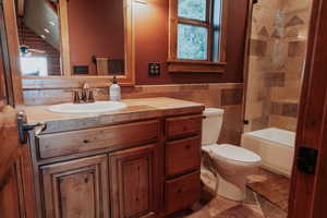 Full bathroom with vanity, tile walls, wainscoting, shower / bathtub combination, and ceiling fan