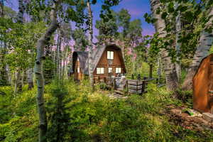 Back of property at dusk featuring a gambrel roof and a wooden deck