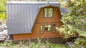 View of home's exterior with a metal roof, a gambrel roof, and a deck