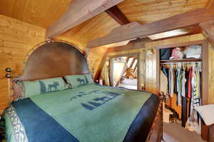 Carpeted bedroom featuring wooden walls, wood ceiling, and a closet