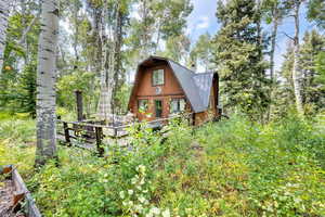 Rear view of house featuring a gambrel roof, a metal roof, and a deck