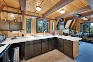 Kitchen featuring wooden walls, a wood ceiling with exposed beams, range, healthy amount of natural light, and light countertops
