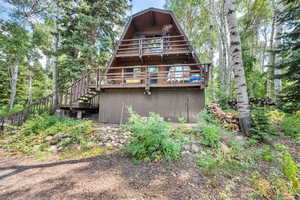 Rear view of house with stairs and a wooden deck
