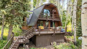 Back of property featuring a metal roof, stairs, and a deck