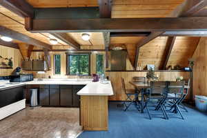 Kitchen featuring electric range oven, a wooden ceiling with exposed beams, wooden walls, black microwave, and a peninsula