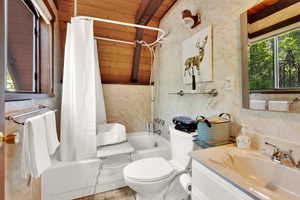 Bathroom with plenty of natural light, vanity, shower / tub combo, and a wood ceiling with exposed beams