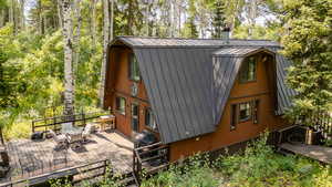 View of home's exterior with a gambrel roof, a metal roof, outdoor dining area, and a deck
