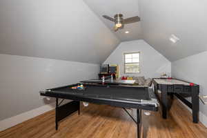 Recreation room with baseboards, a ceiling fan, wood finished floors, and lofted ceiling