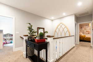 Hallway featuring visible vents, baseboards, an upstairs landing, carpet floors, and recessed lighting