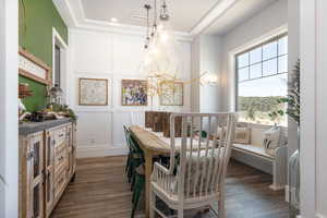 Dining space featuring a decorative wall, dark wood-style floors, and a raised ceiling