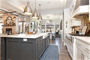 Kitchen featuring white cabinetry, custom exhaust hood, appliances with stainless steel finishes, a sink, and gray cabinetry
