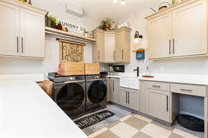 Washroom with washer and dryer, a sink, light floors, and cabinet space