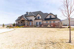 View of front of home featuring roof with shingles, stucco siding, stone siding, and a front lawn