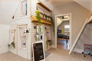 Interior space featuring carpet, baseboards, and lofted ceiling