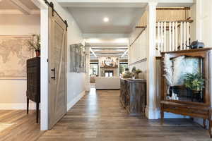 Hall with baseboards, a barn door, and wood finished floors