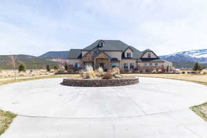 French country inspired facade featuring curved driveway, a mountain view, and stone siding