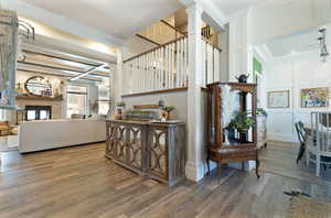 Stairs with a chandelier, ornate columns, coffered ceiling, a decorative wall, and wood finished floors