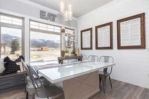 Dining area with dark wood-type flooring, crown molding, a healthy amount of sunlight, and a mountain view