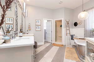 Bathroom with a freestanding tub, a stall shower, wainscoting, visible vents, and a sink