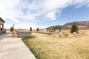 View of yard with a mountain view, a playground, and a hot tub