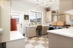 Kitchen featuring gray cabinetry, light countertops, washing machine and clothes dryer, and light floors