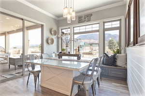 Dining area with a notable chandelier, a mountain view, ornamental molding, and wood finished floors