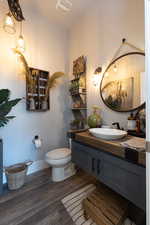 Bathroom featuring vanity, visible vents, toilet, wood finished floors, and baseboards
