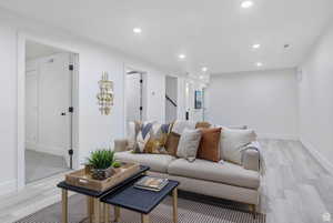 Living room featuring light wood-style flooring, recessed lighting, and stairway