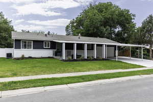 Ranch-style house featuring an attached carport, an attached garage, concrete driveway, brick siding, and roof with shingles