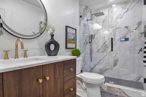 Bathroom with vanity and a marble finish shower