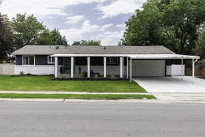 Single story home featuring brick siding, driveway, an attached garage, an attached carport, and a chimney