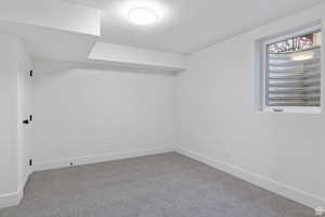 Carpeted spare room featuring baseboards and a textured ceiling