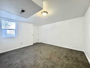 Empty room with a textured ceiling and dark carpet