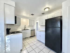 Kitchen with freestanding refrigerator, white cabinets, light countertops, and light tile patterned floors