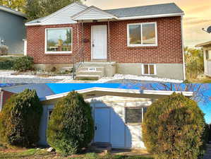 View of front of home with brick siding and roof with shingles