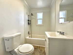 Bathroom featuring a textured wall, ornamental molding, vanity, and shower / washtub combination