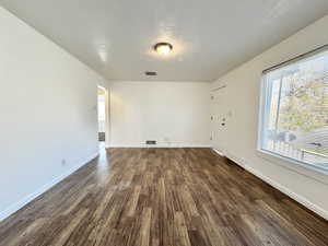 Unfurnished living room featuring a textured ceiling and dark wood-style floors