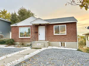 View of front facade with brick siding and a shingled roof