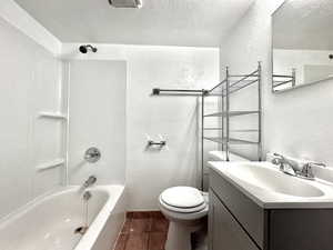 Full bath featuring a textured wall, a textured ceiling, vanity, tile patterned flooring, and shower / washtub combination