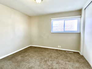 Carpeted spare room featuring baseboards