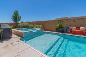 View of swimming pool featuring a pool with connected hot tub and grilling area