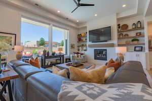 Living area featuring a fireplace, ceiling fan, built in shelves, wood finished floors, and recessed lighting