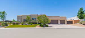 Southwest-style home featuring a garage, stucco siding, and driveway