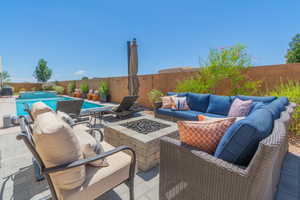 Fenced backyard with an outdoor living space with a fire pit, a patio, a pool with connected hot tub, and grilling area