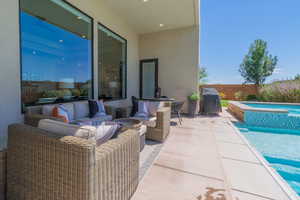 View of patio featuring an outdoor living space, a pool with connected hot tub, and area for grilling