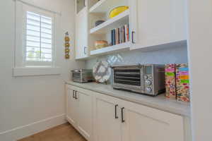 Bar with wood finished floors and tasteful backsplash