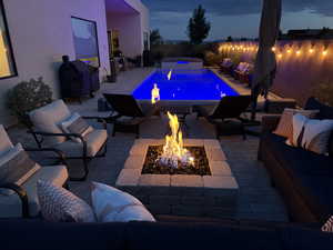 View of swimming pool with an outdoor living space with a fire pit, a patio, and an in-ground hot tub